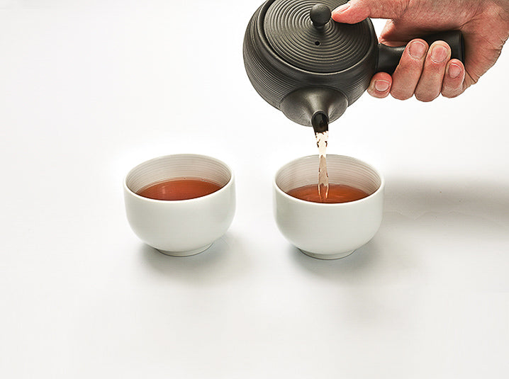 Pouring Hojicha Roasted Green Tea in 2 white cups from teapot