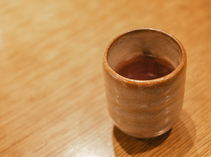 brewed hojicha japanese roasted green tea in a brown glazed ceramic cup