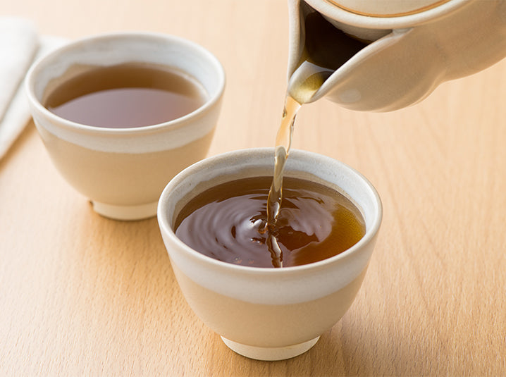 Pouring Hojicha Roasted Green Tea in white cups