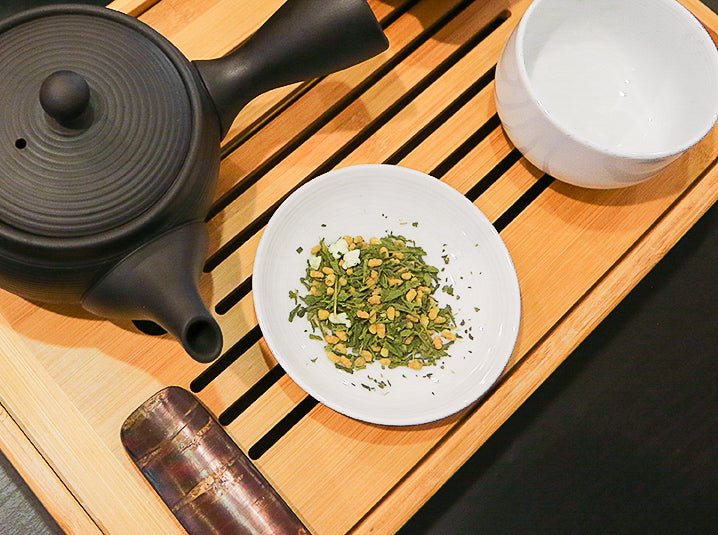 tea leaves in a plate with kyusu teapot and cherry wood tea scoop
