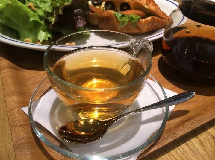 licorice root tea in a glass teacup with spoon for allergies and sore throat relief