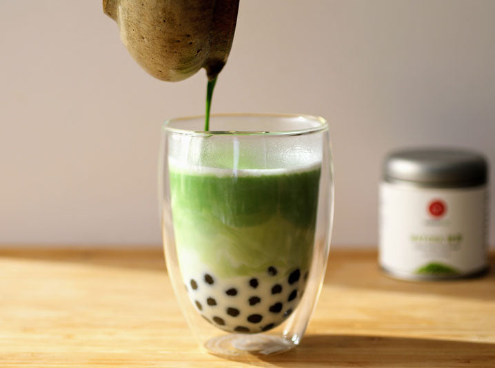 healthy matcha milk bubble tea drink in clear glass with senbird tea matcha can