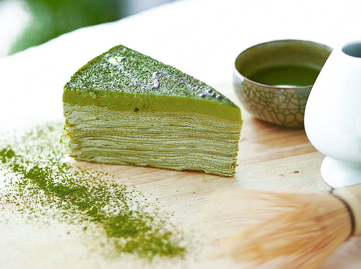 modern cuisine matcha green tea crepe cake with matcha bowl matcha whisk stand on top of a wooden table top