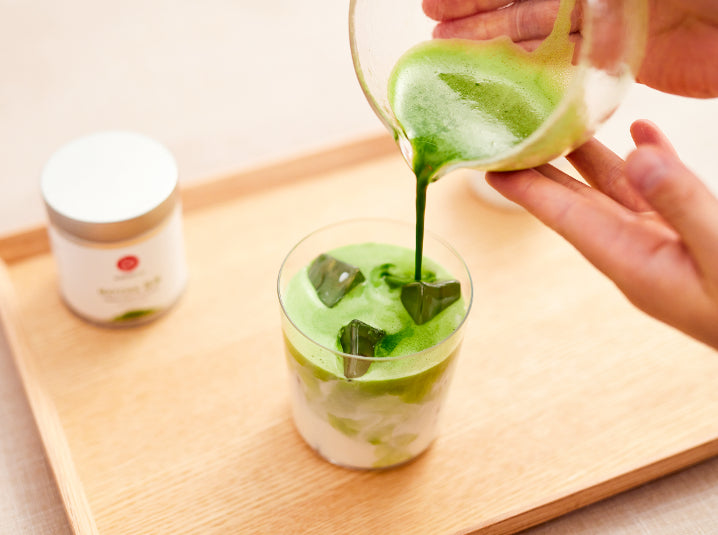 pouring matcha in a glass full of ice with matcha otome tea tin healthy matcha latte drink