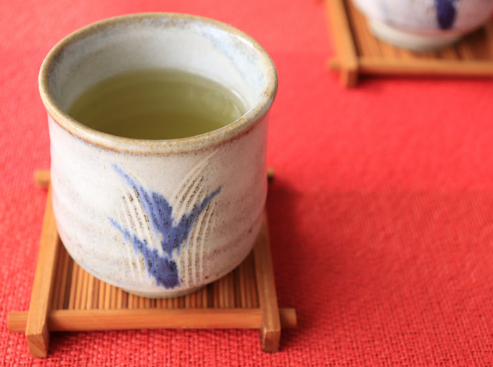 brewed japanese twig tea in a vintage tea cup on top of a wooden coaster