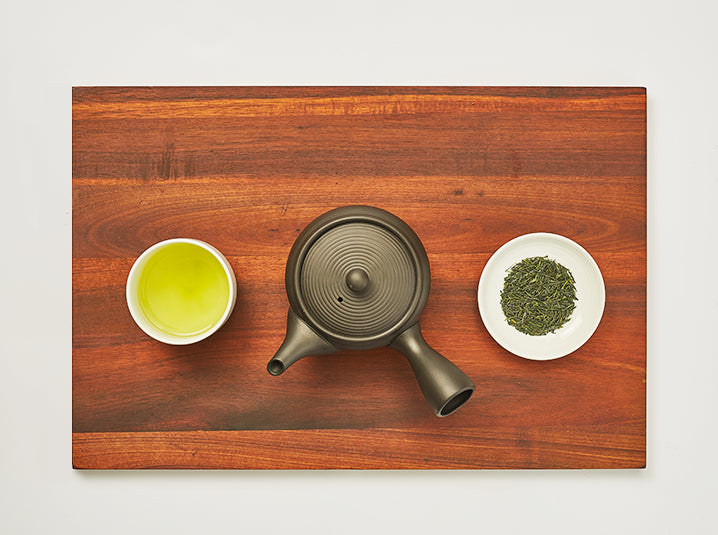 brewed Gyokuro in a cup with kyusu teapot and Gyokuro tea leaves in a plate