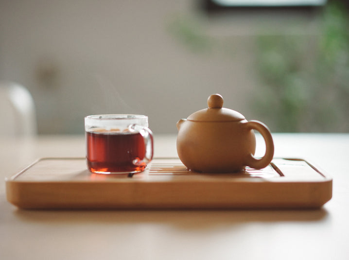 Brewed tea in a cup beside teapot on a tray
