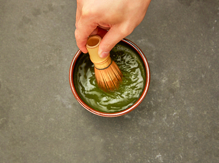 Hands whisking matcha in a bowl