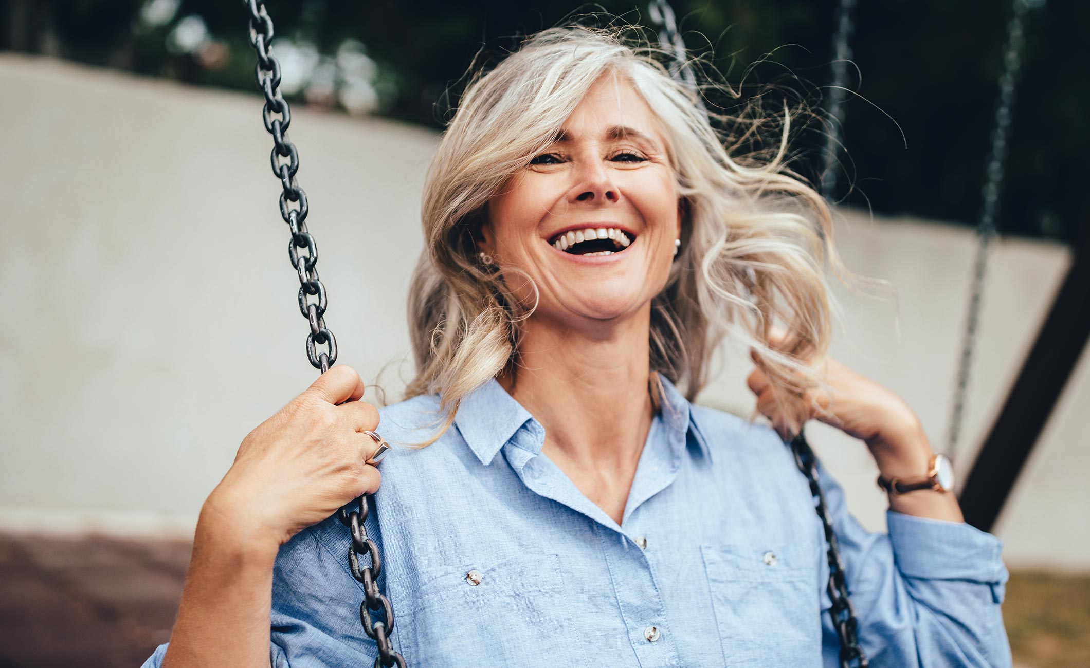 older woman swinging on a swing and smiling 