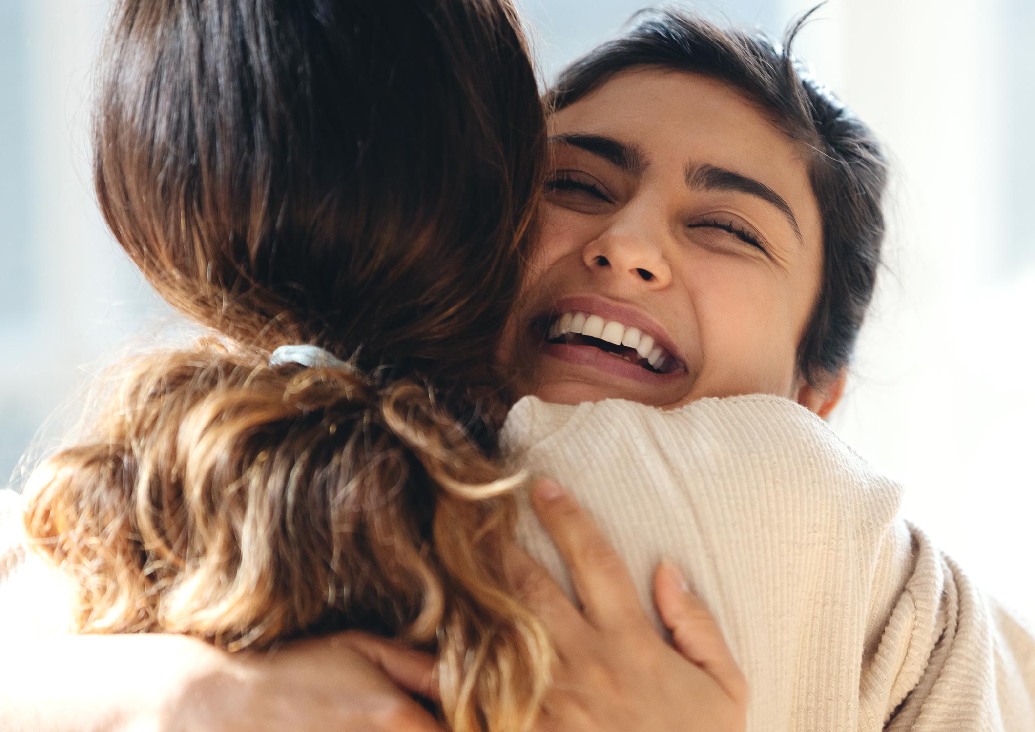close up of two friends hugging and smiling 