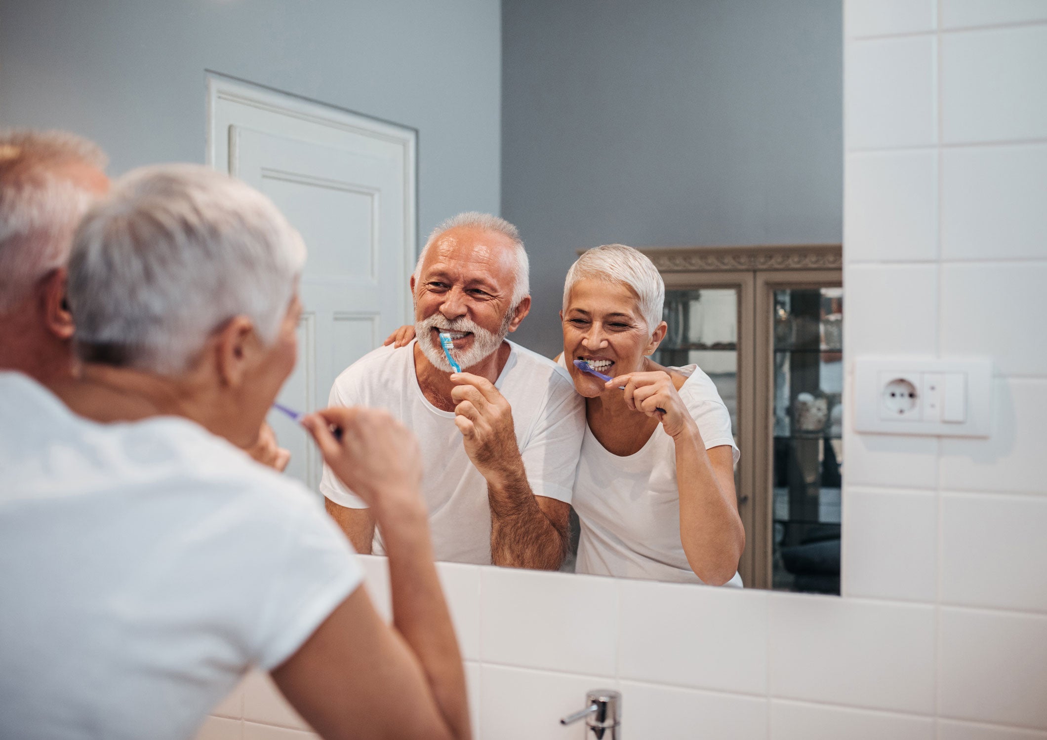 older couple brushing their teeth together and smiling 