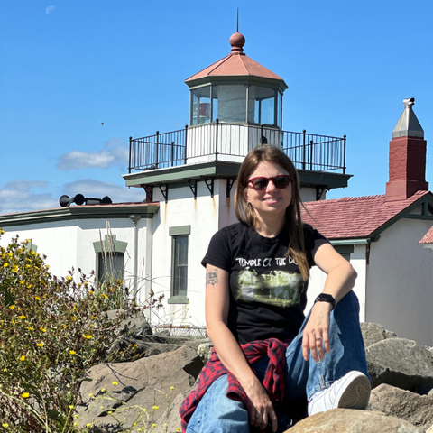 Anita Stelmasiuk, the author of the blog post, sitting casually at Discovery Park in Seattle, wearing a 'Temple of the Dog' T-shirt.