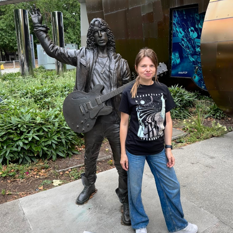 Anita Stelmasiuk posing with the life-size bronze statue of Chris Cornell at the MoPOP Museum in Seattle, a tribute to the iconic musician.