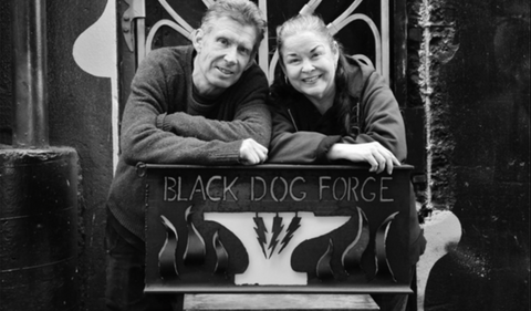 Louie Raffloer and Mary Gioia, founders of Black Dog Forge, posing in front of their shop in Seattle, highlighting the personal connection and history of the iconic forge.