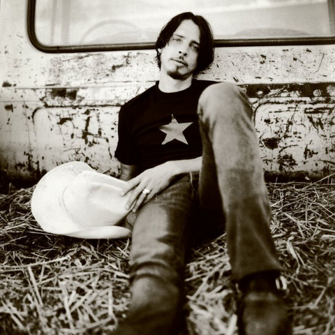 Chris Cornell sitting on hay, holding a cowboy hat at Hidden Hills Ranch