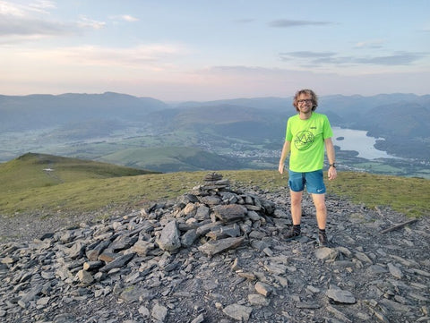 photo of man by cairn of stones in mountains - with Mind Over Mountains mental wellbeing charity