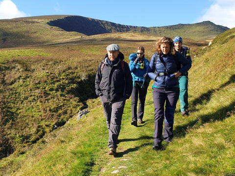 hiking with purpose in Wales - four hikers on grassy path with hills beyond
