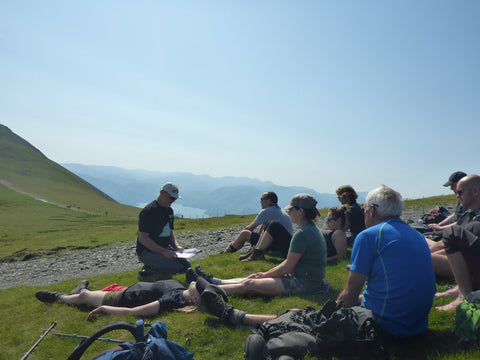 group of hikers practising mindfulness on hillside in lake district during wellness hike