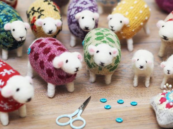 A flock of Mary Kilvert's hand felted sheep in knitted jumpers