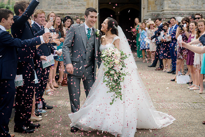 Happy newlyweds being showered in petal confetti from the Shropshire Petals farm