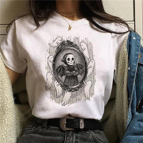 Mujer enseñando camiseta con estampado de unos fantasmas llevando un espejo para que una calavera vampiro se vea en él