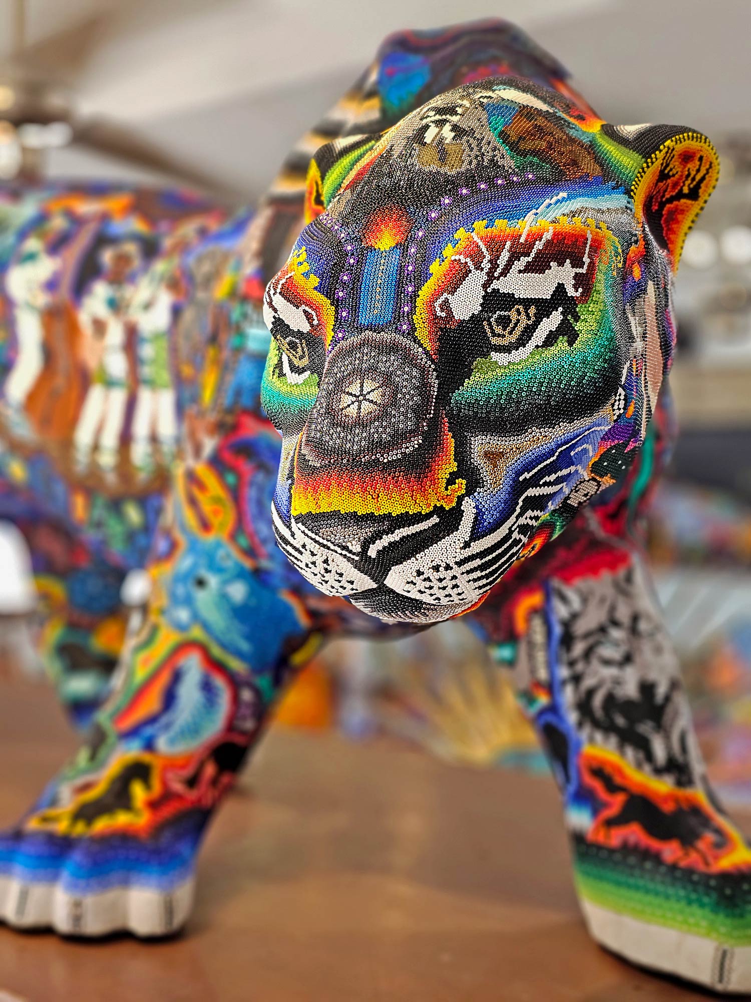 Obra de arte de jaguar en formato escultura grande con patrones y simbolos huicholes de colores vividos