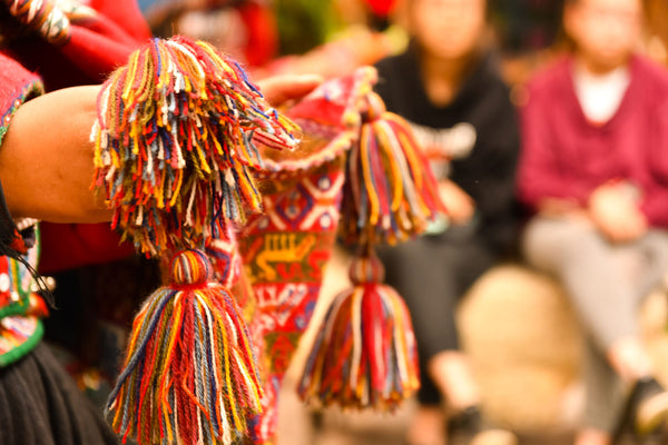 manos de una mujer wixárika con una ofrenda de un tejido de color rojo típico de la cultura huichol