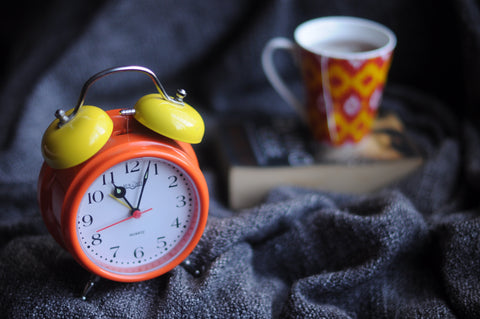 orange and yellow clock next to a cup