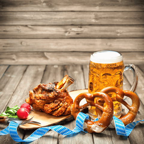 Oktoberfest food showcasing two pretzels, radishes, chicken, and beer