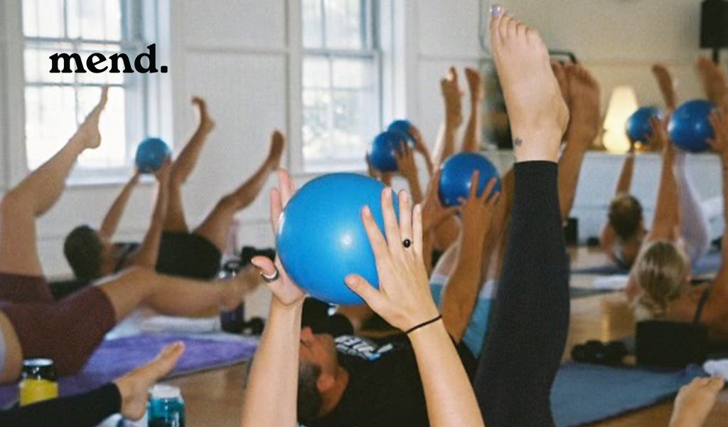 feet in the air hands holding blue exercise ball at mend yoga class
