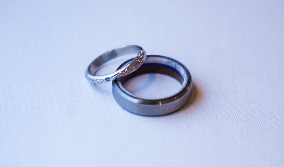 Samantha’s custom sylleblossom inspired wedding ring next to her husband’s wedding band