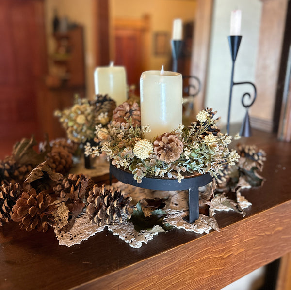 Candle centerpiece with pinecones on mantle