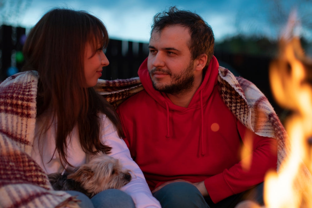 couple sitting in front of fire with Yorkie on woman's lap