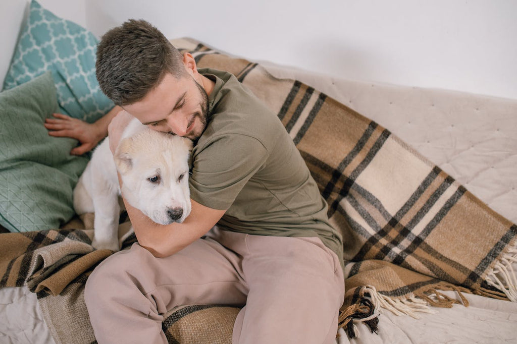 A man hugging his dog with a hair resistant blanket