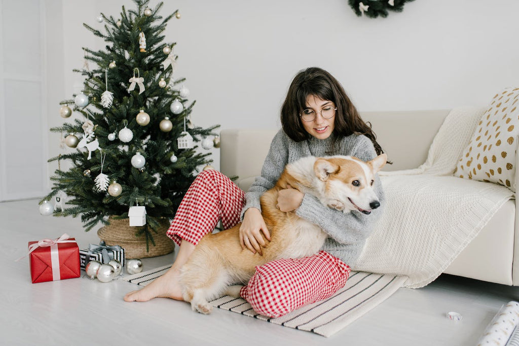 A woman holding her dog near a Christmas tree