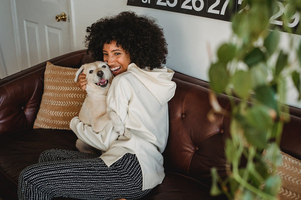 A smiling woman holding on to a small white dog
