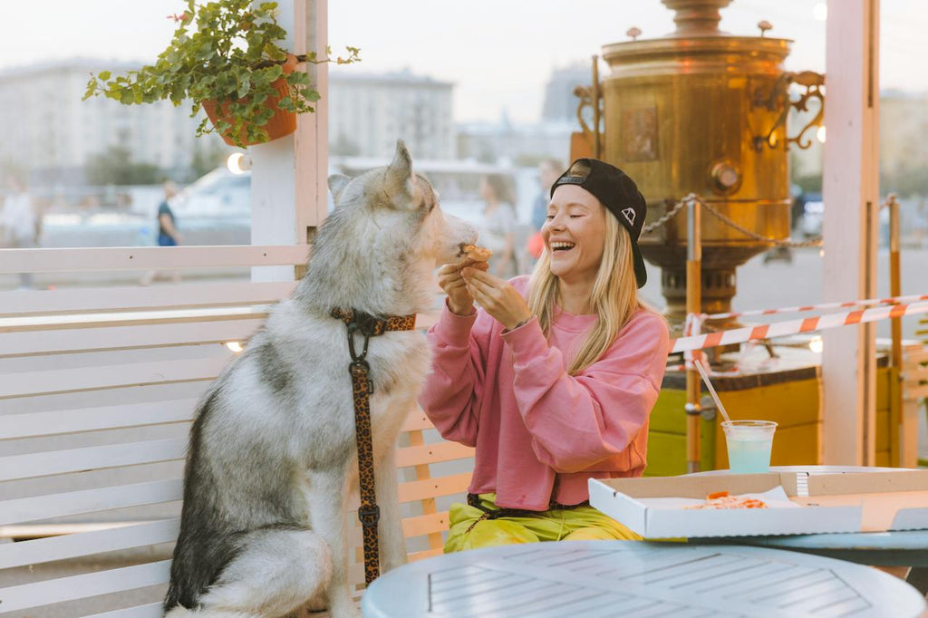 A woman and her dog enjoying a slice of pizza