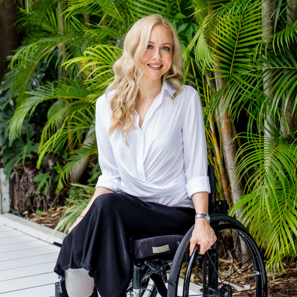 Lisa our size 6 and 8 model wearing our Cate technical shirt in white sitting in her wheelchair