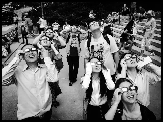group of people wearing eclipse glasses watching sun