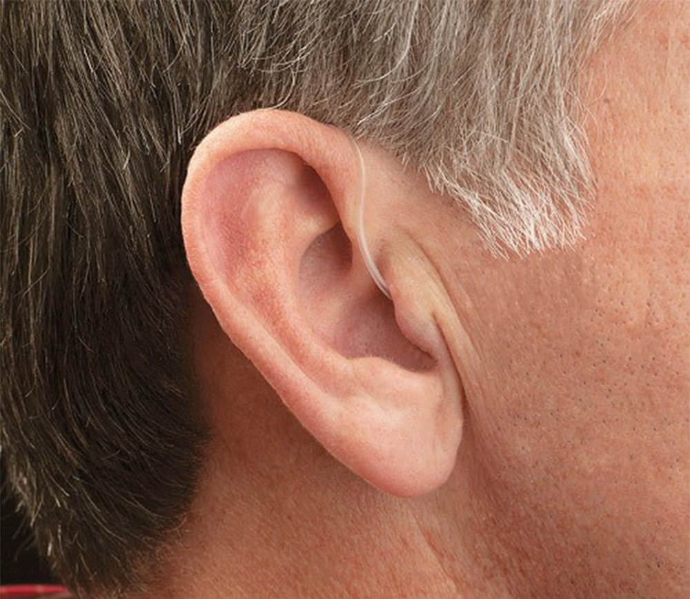 Close-up of a person's ear wearing a behind-the-ear hearing aid.