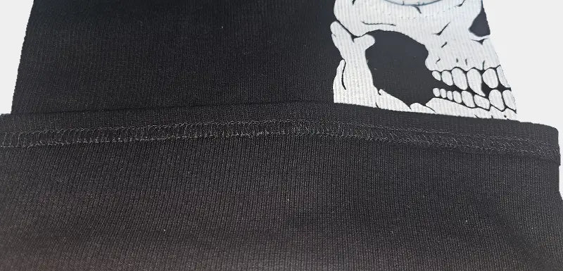 Zoom la maille chaude d'une cagoule militaire noire montrant un motif de crâne blanc partiellement visible, idéal pour un style tactique ou déguisement effrayant.