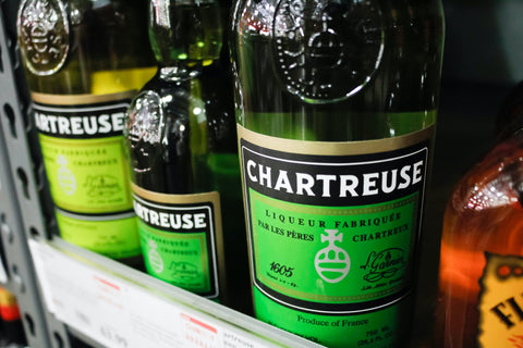 Three green Green Chartreuse bottles on a shop shelf