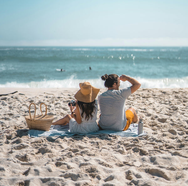 A couple at a beach picnic in boardshorts