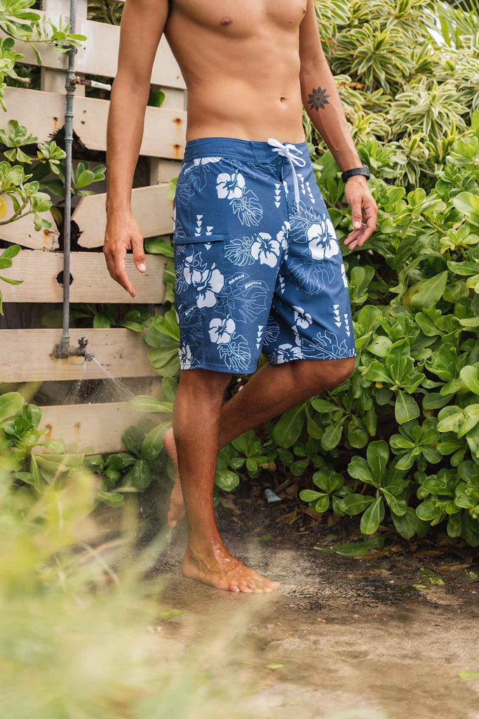 Man wearing hawaiian floral boardshorts in beach shower