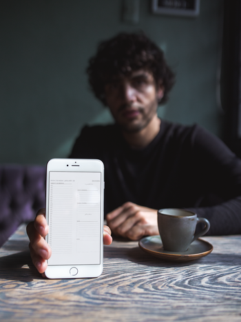 mockup-of-a-man-holding-an-iphone-against-the-table-a21606.png__PID:6494bbe0-89a2-4a51-a220-71e77a973730