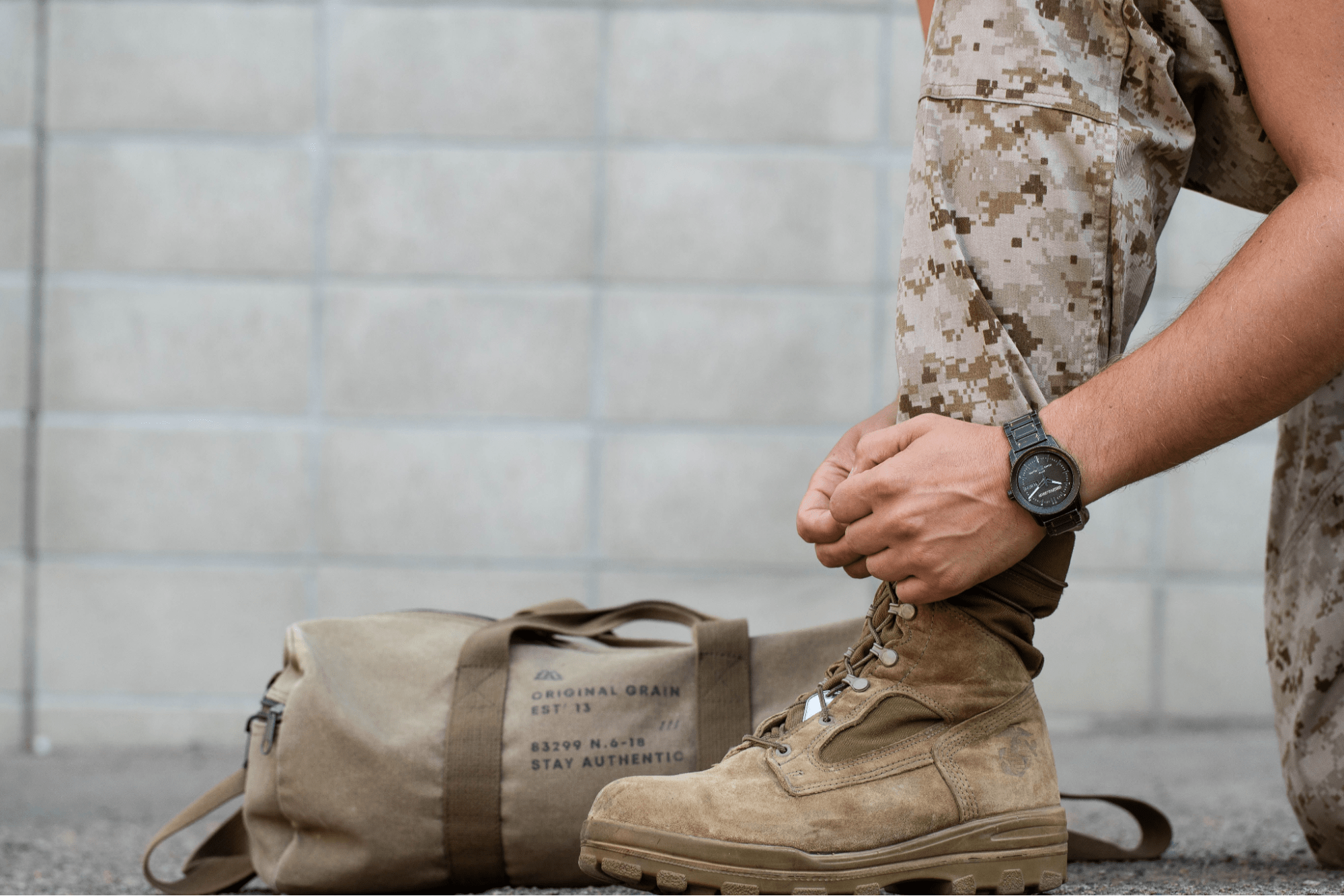 Image of a military dad wearing an Original Grain watch and tieing his boots