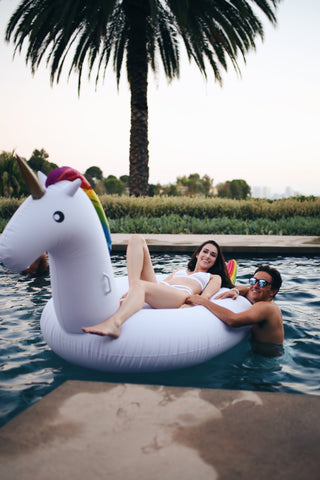 Kololo Giant Unicorn rainbow floaty pool party girl lounging guy next to floaty