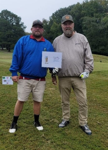 Photo of Lucas and Cliff holding certificate and dressed in golf clothes