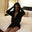 Cindy Bruna on a bed wearing a black Jitrois dress in leather and black gloves