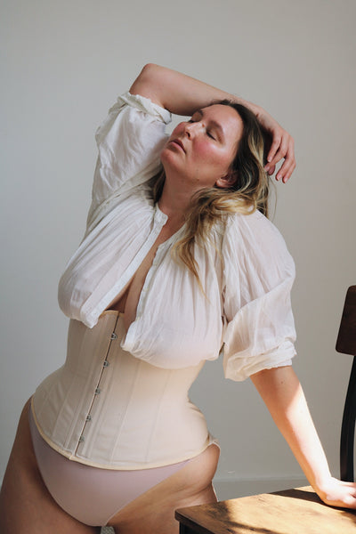Elly wears a Heledd corset in beige with a white shirt